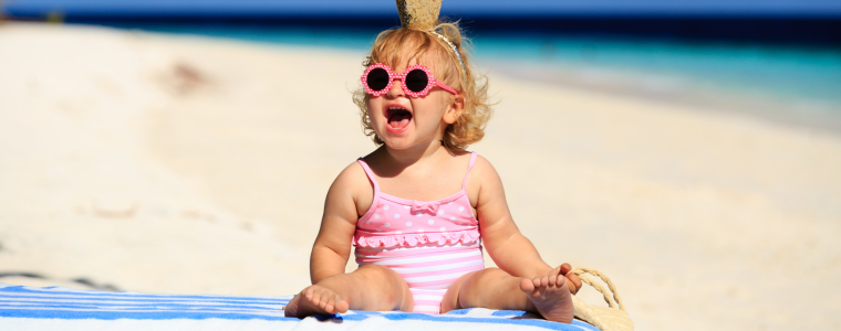 Image colorée. Bébé fille sur la plage avc des lunettes de soleil. 
