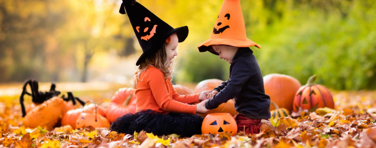 Enfants en chapeaux de sorcière profitant de snacks Halloween sains, entourés de citrouilles.