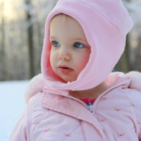 Bébé emmitouflé dans une combinaison chaude, un des indispensables pour l'hiver