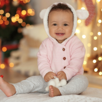 Comment choisir un cadeau de Noël pour bébé : illustration avec un bébé joyeux en décor festif.