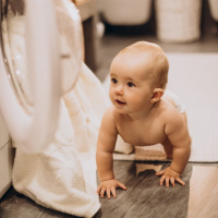 bébé devant une machine à laver, la maman lave le linge de bébé