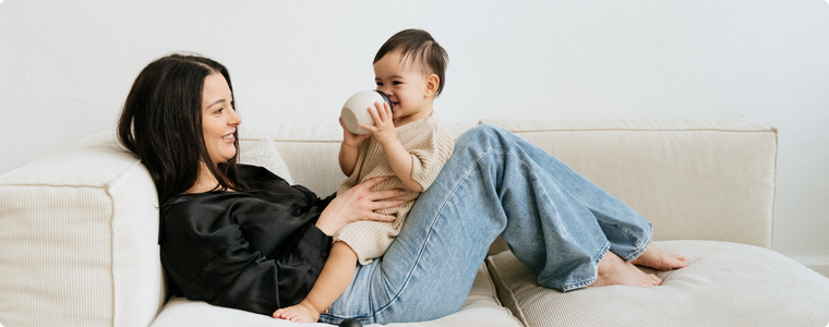 Maman et bébé sur le canapé ; stériliser le biberon pour une tétée sereine.