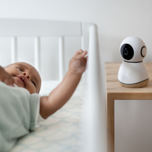 Bébé allongé dans son lit avec un babyphone caméra à proximité.