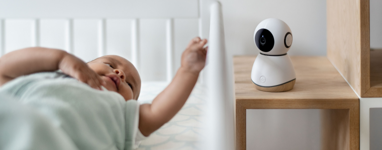 Bébé allongé dans son lit avec un babyphone caméra à proximité.