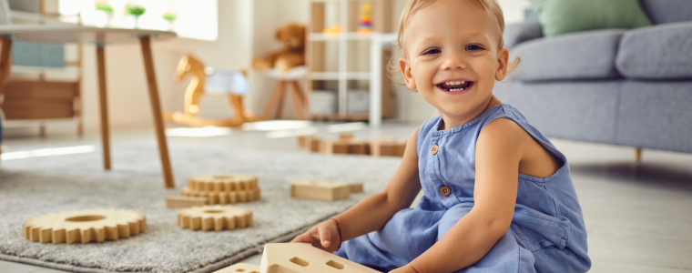 Bébé souriant jouant avec des blocs en bois à la crèche