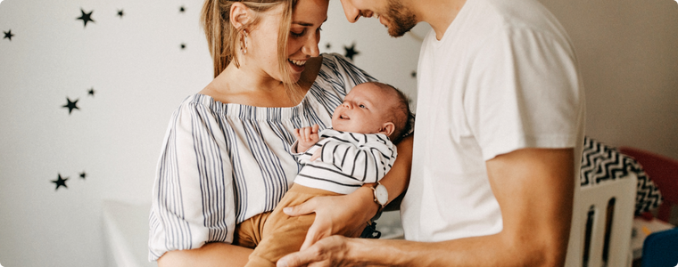 jeunes parents souriants tenant leur bébé dans la chambre, moment de tendresse — phrases positives parents