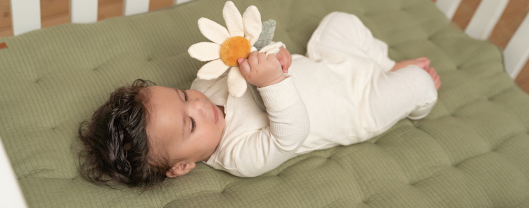 Bébé de 6 mois tenant un jouet d’éveil en forme de fleur.