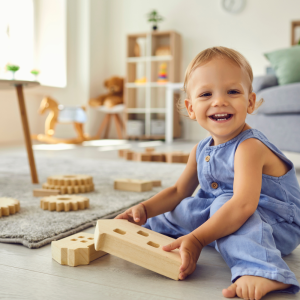 Bébé souriant jouant avec des blocs en bois à la crèche