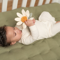 Bébé de 6 mois tenant un jouet d’éveil en forme de fleur.
