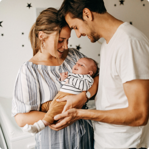 jeunes parents souriants tenant leur bébé dans la chambre, moment de tendresse — phrases positives parents